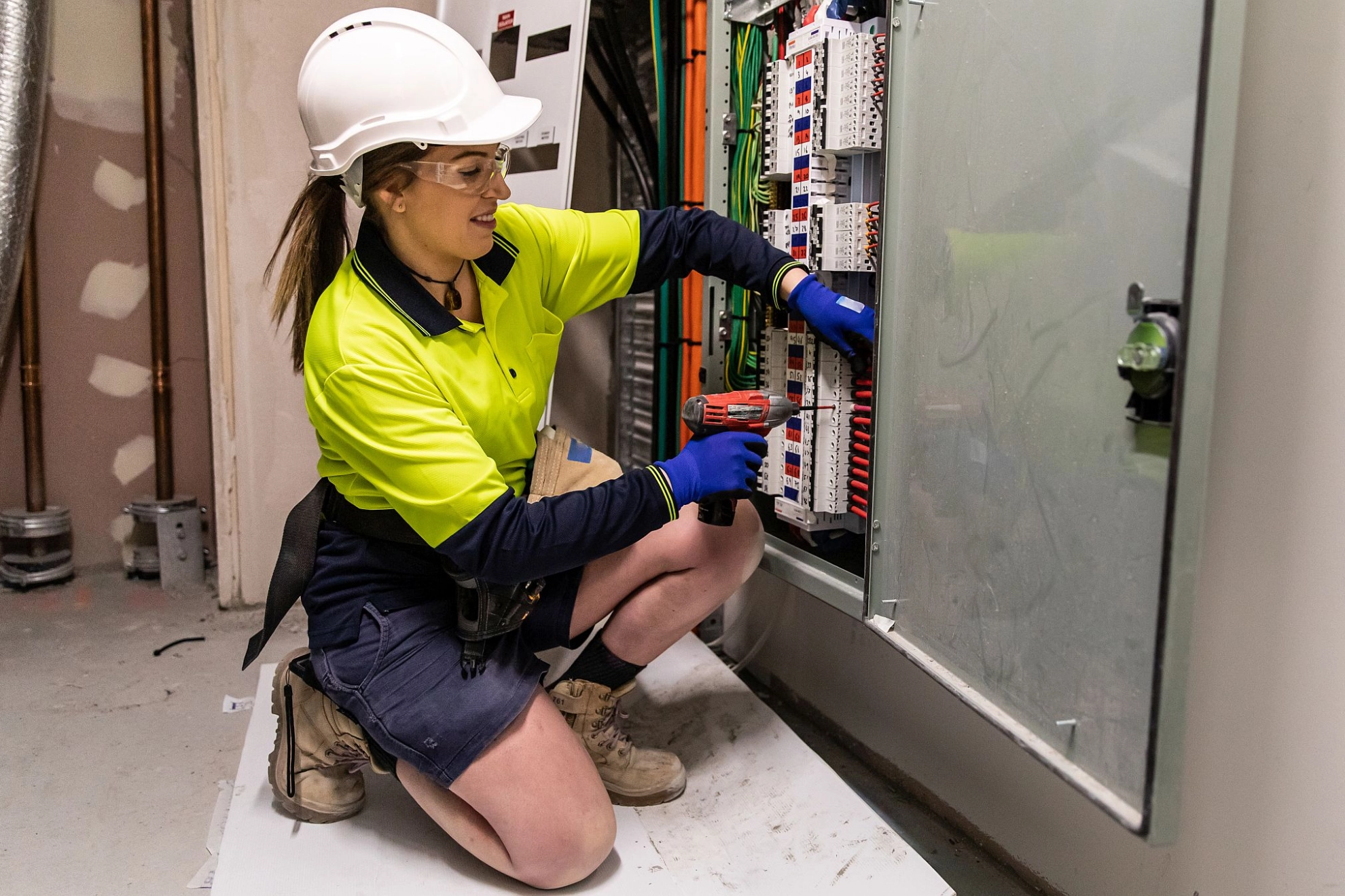 Elektrohandwerkerin arbeitet am Verteilerkasten